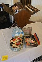 Open cantilever sewing box with two tins on table