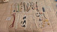 All jewelry pieces laid out on bed showing variety of necklaces, brooches, pins and earrings