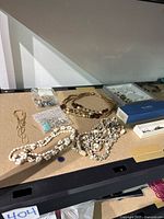Overview of mixed necklaces, bracelets, rings, earrings on tabletop