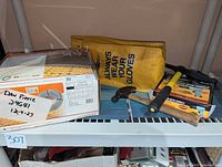 All items on shelf: Schluter cable box, yellow glove bag, hammers, pick, air hammer kit