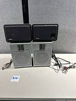 Front view of two Bose Video RoomMate speakers stacked on two Soundesign 0609 speakers with wiring visible