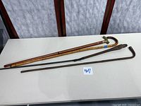 Three canes laid out: bamboo, curved wood, plain rod