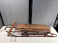 Full view of Columbia Flyer sled side angle showing wooden deck, steel runners, steering bar, rope
