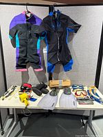 Overview of entire lot on table and hanging wetsuits