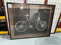 Full view of framed bicycle print leaning against shelving