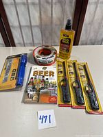 All items grouped: Goo Gone bottle, Gorilla Tape roll, blue packaged flashlight, three lighters in packages, beer book