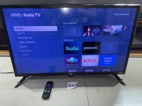 Front view of 32-inch Onn Roku TV powered on, showing interface and remote
