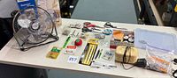 Overall lot view with fan, bobbin winder and assorted sewing supplies on table