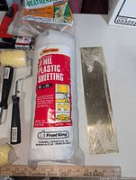 Plastic sheeting roll and metal straightedge