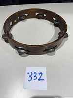 Top view of full tambourine showing circular wood frame and six metal jingle pairs