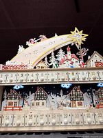 Front close view of wooden advent calendar showing drawers 1-24 and illuminated village scene