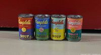 Four unopened Warhol Campbell’s soup cans, front view