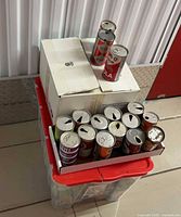 Overall lot showing tray of vintage soda cans and two cans on box