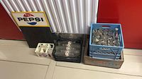 Group view showing Pepsi tin chalkboard, blue crate with bottles inside wood Kist crate, black crate with bottles, white Pepsi carrier