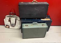 Group shot of all four luggage pieces: Adidas bag, black hard case, navy trunk, sage suitcase