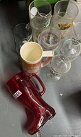 various glasses including red boot mug, ceramic stein, pint and stem glasses