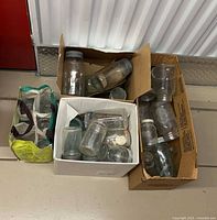 Four cartons filled with clear glass mason jars of assorted sizes with metal lids