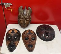 Group shot of four carved wooden masks on table