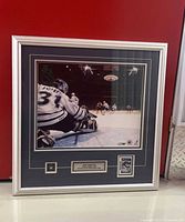Overall framed display showing photograph, pin, card and plaque