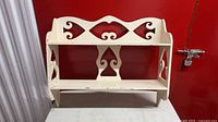 Front view of carved white painted wall shelf showing overall design and two shelves