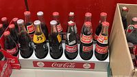 Front view of 12 unopened Coca-Cola bottles in cardboard tray