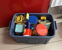 Plastic tote holding various vintage tins and packaging