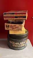 Stacked view showing Moonlight Mellows tin, Bridge Mixture box, Jenny Lind box, two Oh Henry boxes