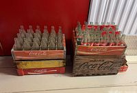 Two Coca-Cola wooden crates filled with clear and labelled bottles