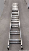 Full view of the ladder fully extended showing aluminum rungs and sections separated by locking hinges.