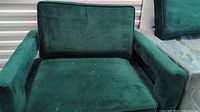 Front view of one green velvet lounge sofa showing seat and back cushions and armrests.