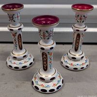 Three vintage Czech Bohemian glass candle holders showing their overall shape and painted floral design.