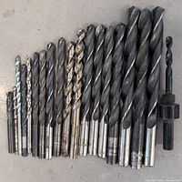 Row of drill bits arranged from smallest to largest including various sizes and shank types