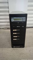 Front view of Microboards DVD duplicator tower with LCD display, control buttons, and 7 DVD drives labeled Master and Copies 1-6.