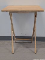 Front view of the foldable wooden tray table showing rectangular top and legs