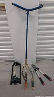 Full view of gardening tools including cultivator, pruners, hedge shears, sprinkler