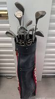 Front view of golf bag showing several golf clubs with metal shafts and heads inserted.