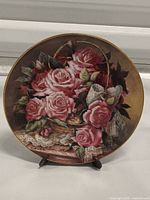 Front view of the porcelain plate showing pink rose basket design with lace bow and gold rim.