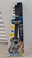 Front view of kids acoustic guitar in original First Act Discovery packaging showing complete guitar and branding.