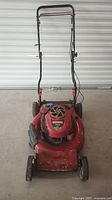 Front view of red Craftsman lawn mower showing the handlebar, wheels, and mower deck.