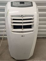Front view of white LG portable air conditioner showing vent louvers and control panel.