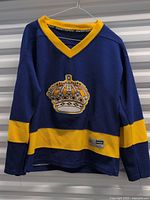 Front view of blue Los Angeles Kings retro hockey jersey with yellow collar and sleeve detail, crown logo on chest.