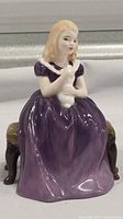 Front view of Royal Doulton Affection figurine showing young girl in purple dress holding white cat.