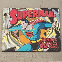 Front cover of the hardcover book showing Superman in a blue suit with red cape breaking through a wall, titled 'Superman Sunday Classics 1939-1943'