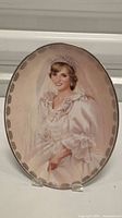 Collector plate depicting Princess Diana in her wedding dress, smiling, with a decorative border on the ceramic surface.