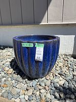 Full view of the large blue ceramic pot placed on rocks outdoors showing the size and shape.