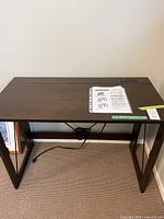 Front view of the dark brown folding laptop desk showing the flat top surface, legs, and power cord underneath.