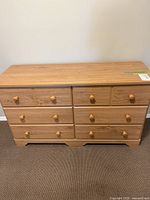 Front view of the wooden dresser showing six drawers with round wooden knobs.