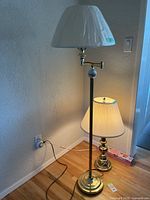 Full view of set with floor lamp and table lamp on hardwood floor against wall, both lit.