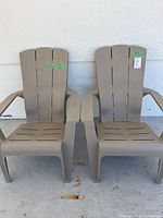 Front view of two beige plastic garden chairs side by side against a white wall