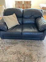 Front-facing view of navy blue leather two-seat sofa with beige cushion on left seat.
